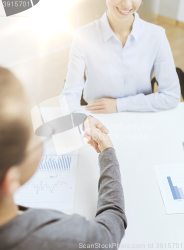 Image of two smiling businesswoman shaking hands in office