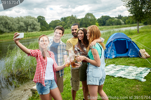 Image of happy friends taking selfie by smartphone at camp