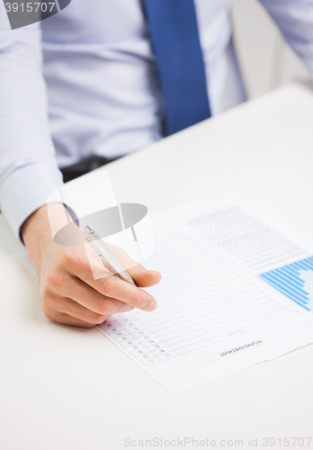 Image of close up of businessman hand with charts in office