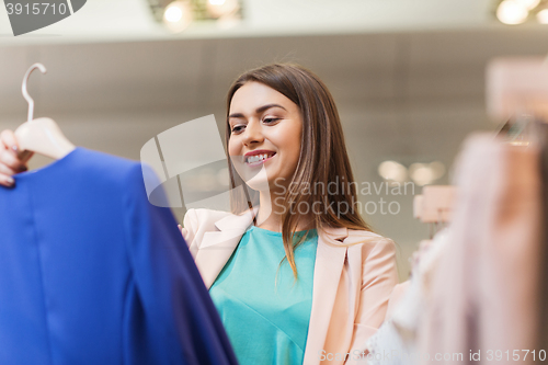 Image of happy young woman choosing clothes in mall