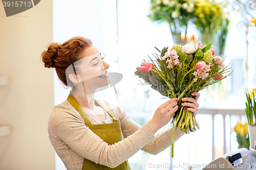 Image of smiling florist woman making bunch at flower shop