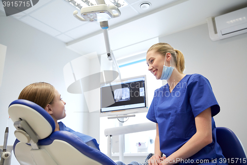 Image of happy female dentist with patient girl at clinic