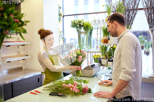 Image of smiling florist woman and man at flower shop