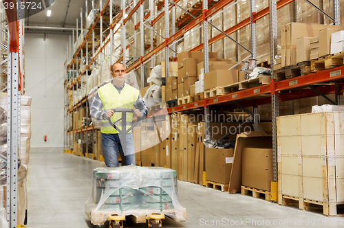 Image of man carrying loader with goods at warehouse