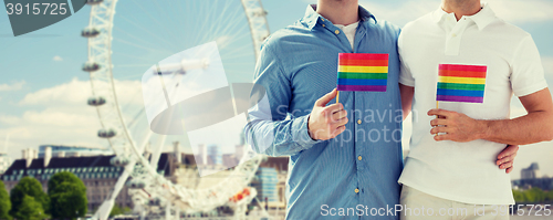 Image of close up of male gay couple with rainbow flags