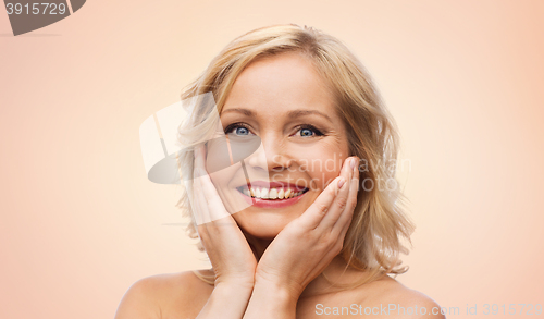 Image of smiling woman with bare shoulders touching face