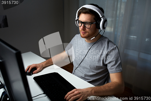 Image of man in headset playing computer video game at home