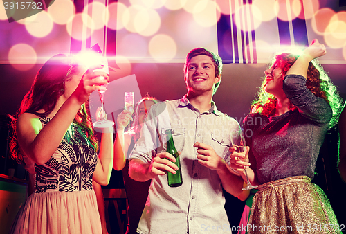 Image of smiling friends with wine glasses and beer in club