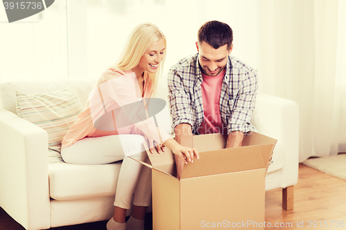 Image of happy couple with cardboard box or parcel at home