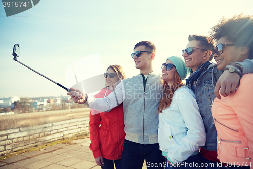 Image of smiling friends taking selfie with smartphone