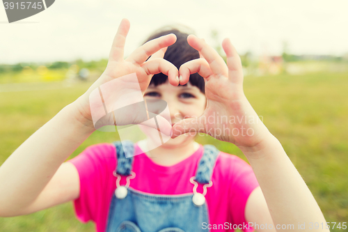Image of happy little girl making heart shape gesture