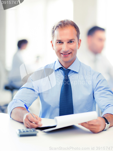 Image of businessman with notebook and calculator in office
