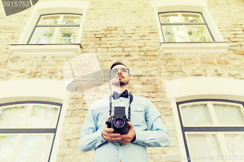 Image of happy young hipster man with film camera in city