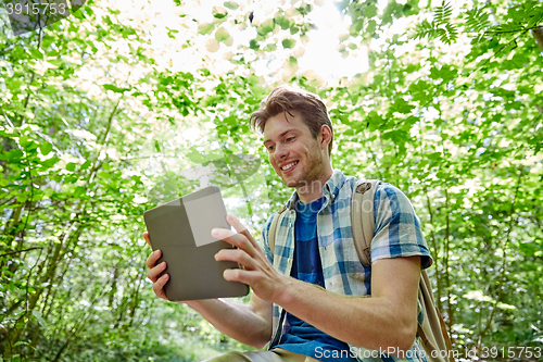 Image of happy man with backpack and tablet pc in woods