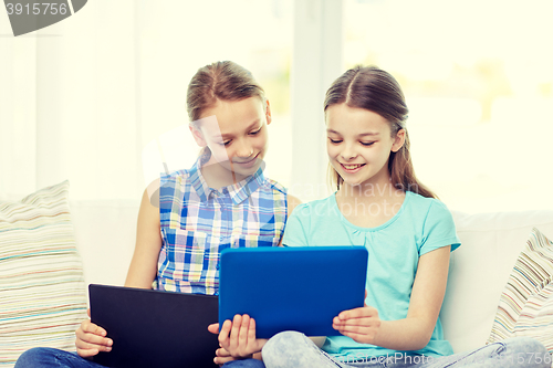 Image of happy girls with tablet pc sitting on sofa at home