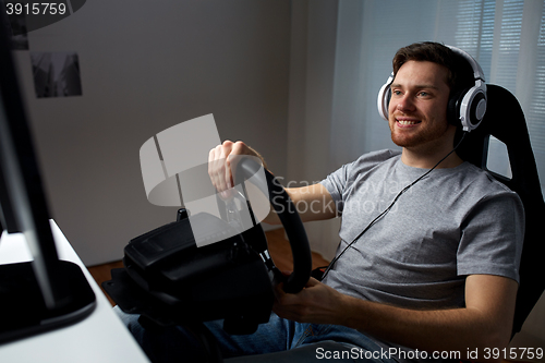 Image of man playing car racing video game at home