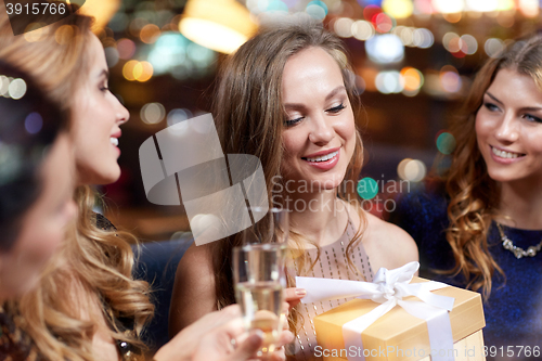 Image of happy women with champagne and gift at night club