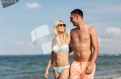 Image of happy couple in swimwear walking on summer beach