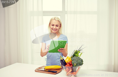 Image of smiling young woman with tablet pc cooking at home