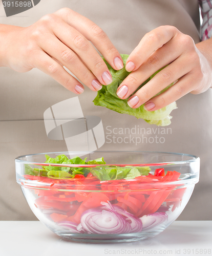 Image of Cook is tearing lettuce while making salad