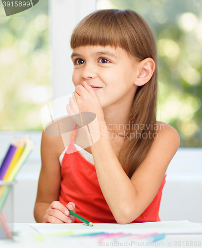 Image of Little girl is drawing using pencils