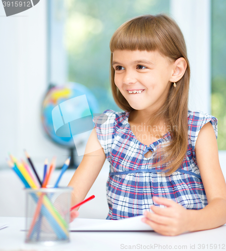 Image of Little girl is drawing using pencils