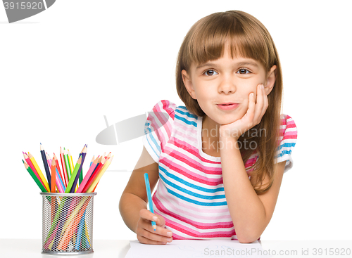 Image of Little girl is drawing using pencils