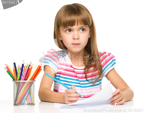 Image of Little girl is drawing using pencils