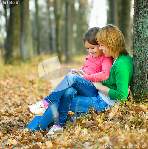 Image of Mother is reading from tablet with her daughter