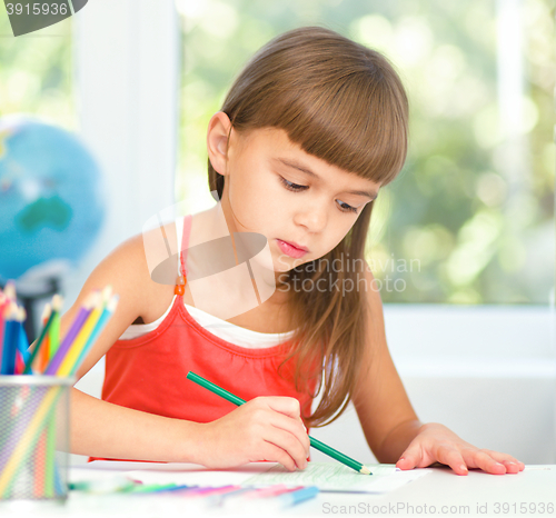 Image of Little girl is drawing using pencils