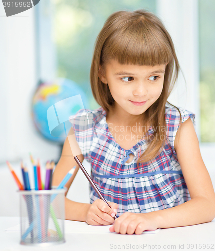 Image of Little girl is drawing using pencils