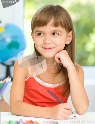 Image of Little girl is drawing using pencils