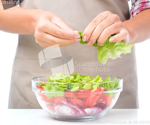 Image of Cook is tearing lettuce while making salad