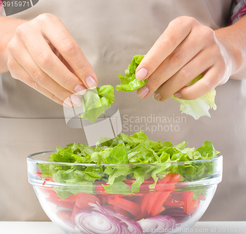 Image of Cook is tearing lettuce while making salad