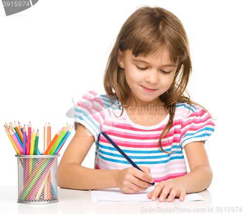 Image of Little girl is drawing using pencils