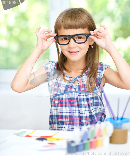 Image of Little girl is painting with gouache