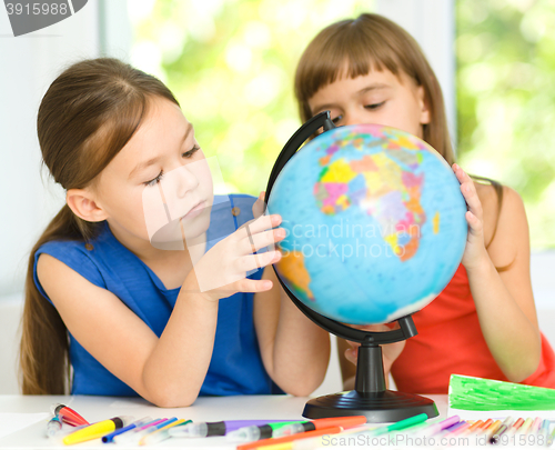 Image of Little girls are examining globe