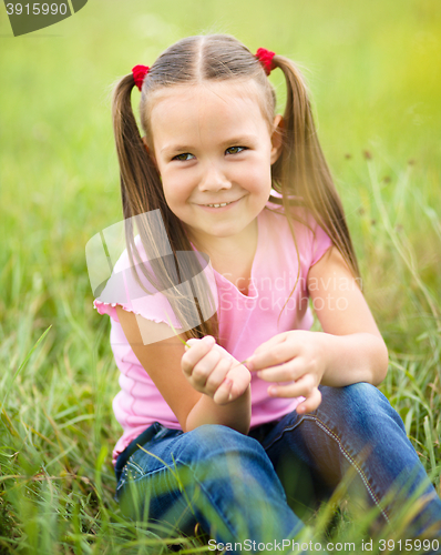 Image of Portrait of a little girl sitting on green grass
