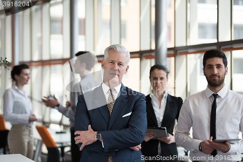 Image of portrait of senior businessman as leader  with group of people i