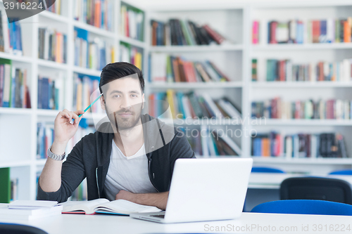 Image of student in school library using laptop for research