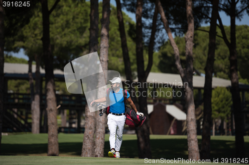 Image of golf player walking and carrying bag