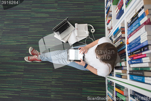 Image of female student study in library, using tablet and searching for 