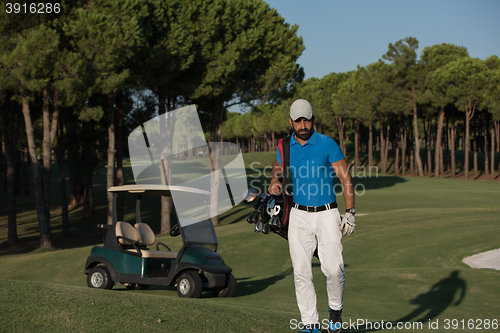 Image of golfer  walking and carrying golf  bag