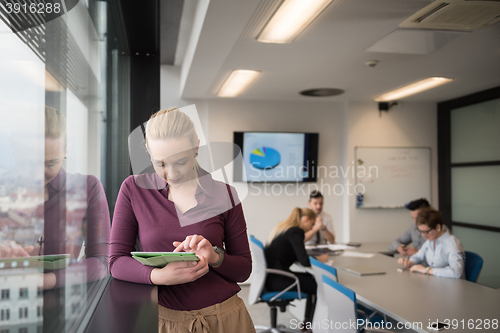 Image of blonde businesswoman working on tablet at office