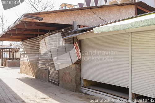 Image of Closed trade pavilions and boarded metallosayding building a sidewalk cafe on a deserted seaside street