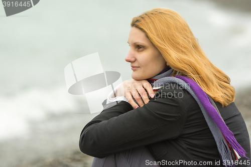 Image of Portrait of enigmatic smiling girl on the background of the surf on a cloudy cold day