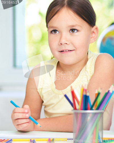 Image of Little girl is drawing using pencils