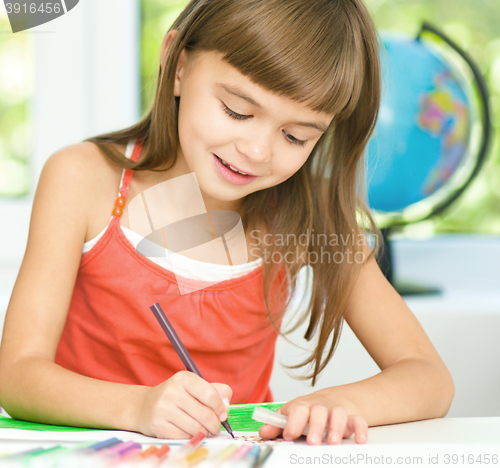 Image of Little girl is drawing using pencils