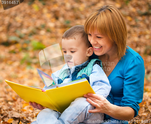 Image of Mother is reading from tablet with her son