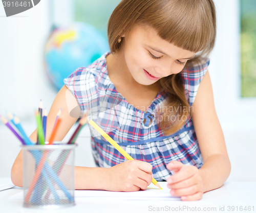 Image of Little girl is drawing using pencils